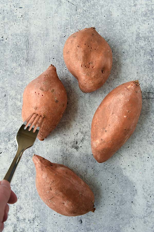 Step one is to clean sweet potatoes and poke holes in them with a fork.