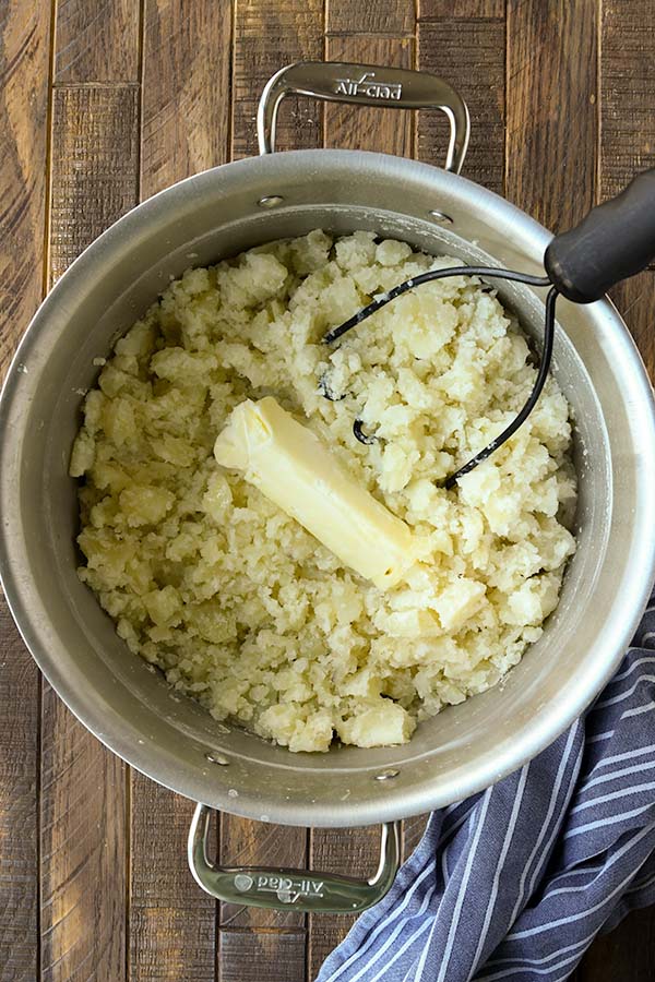 Step four add the butter and cream cheese to the slightly mashed potatoes.