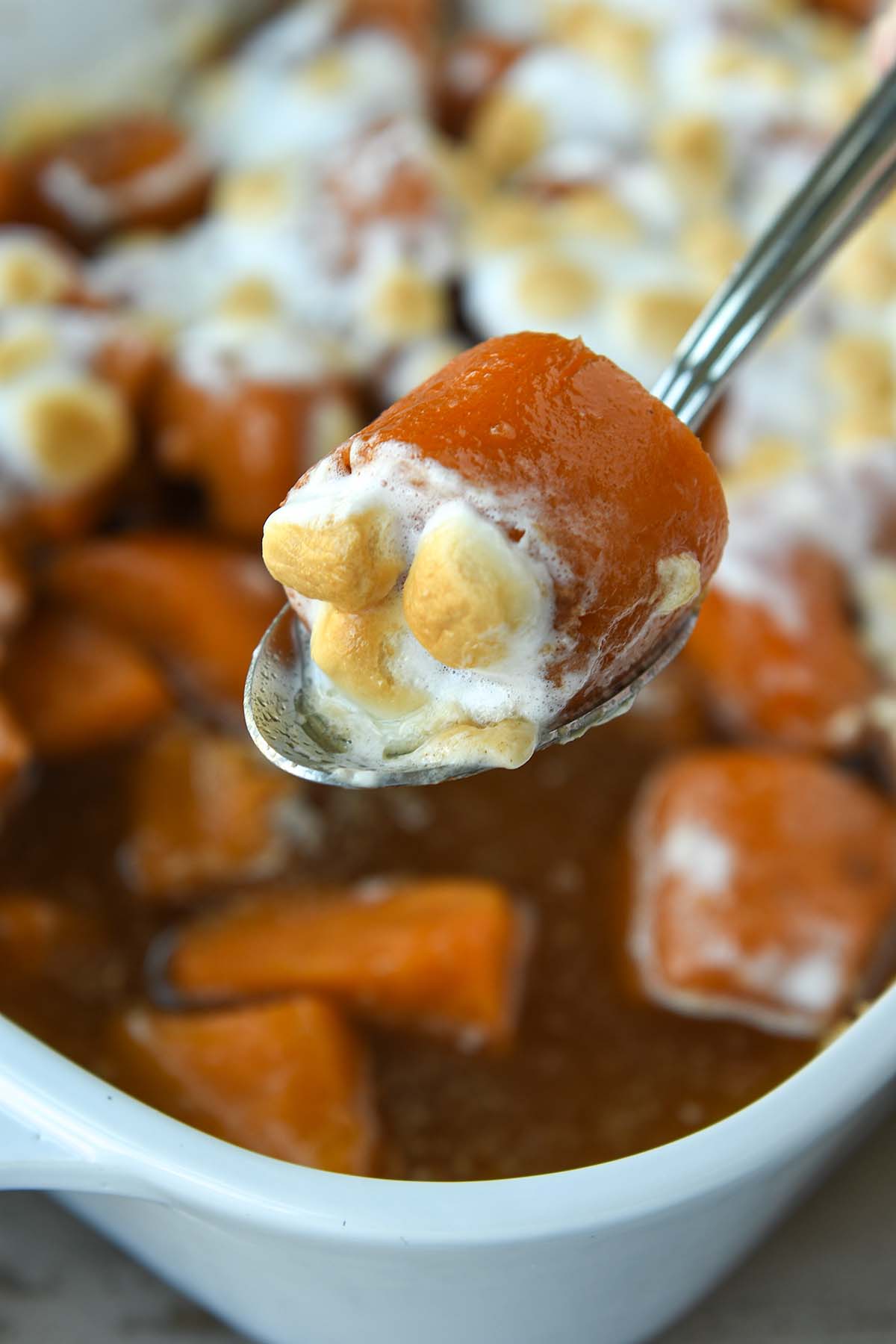 A large chunk of sweet potato with marshmallows on a serving spoon.