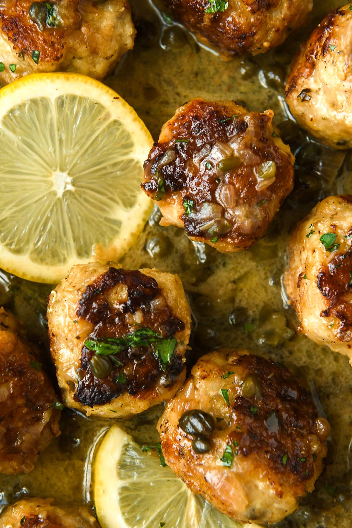 A super up close image of the meatballs with a slice of lemon.