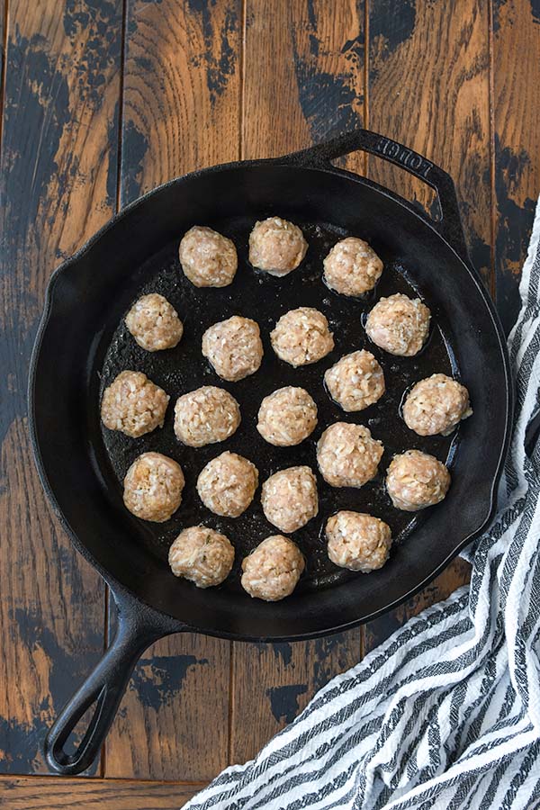 Step two is searing the meatballs in a skillet.