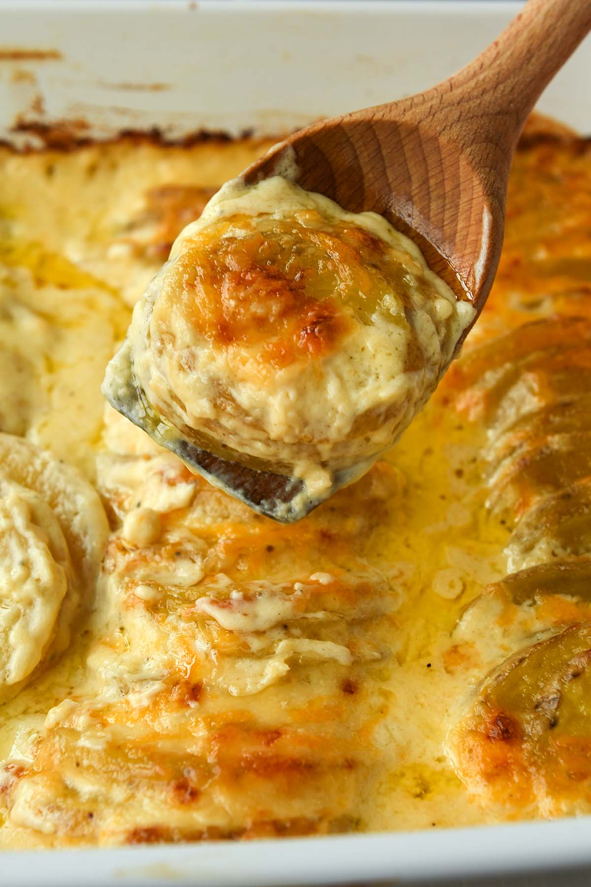 A spoonful of potatoes above a pan of potatoes.