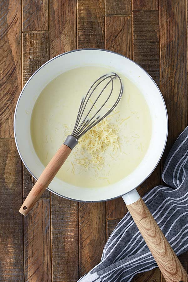 Step four is the shredded cheese added into the sauce with a whisk.