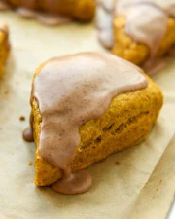 Up close of a pumpkin scone with icing on a baking sheet.