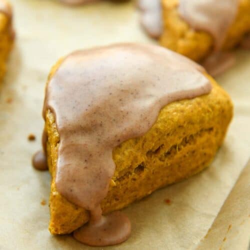 Up close of a pumpkin scone with icing on a baking sheet.