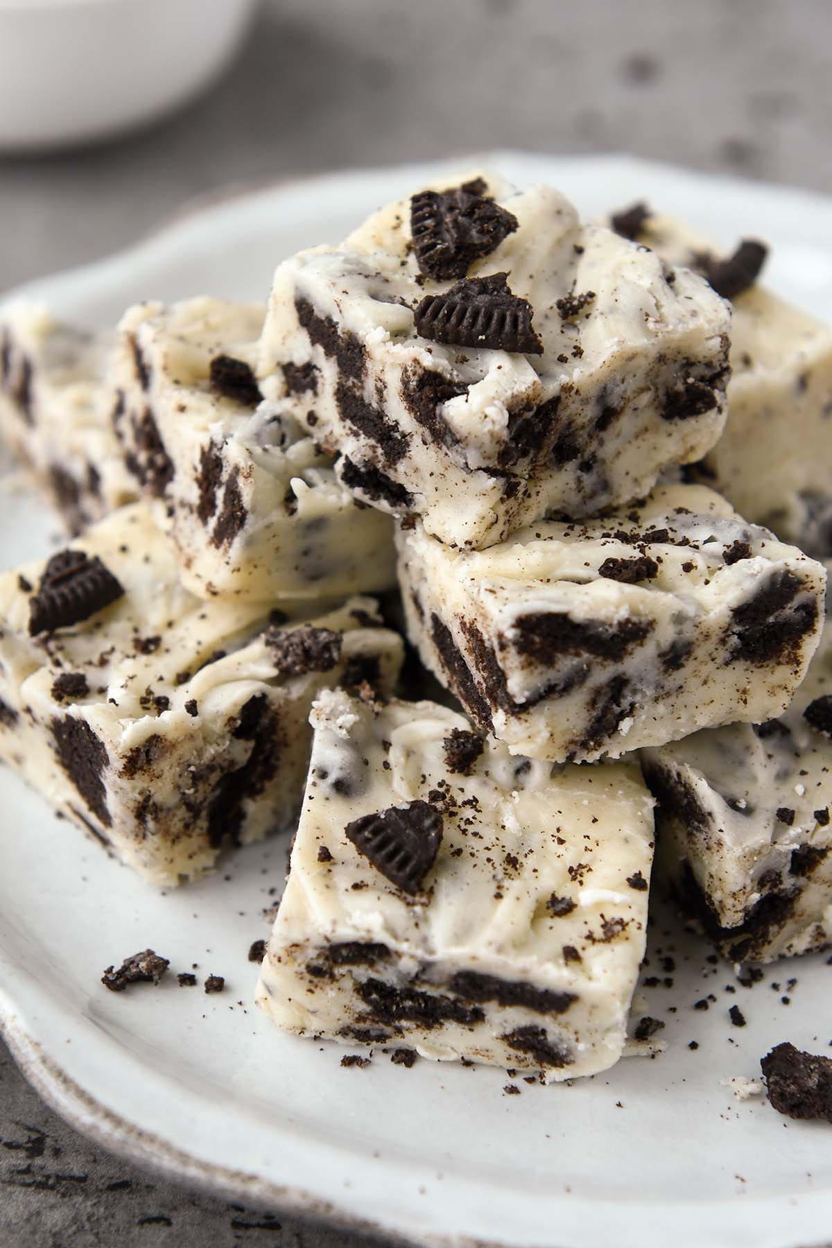 A plate of stacked oreo cookie fudge with some crumbs of Oreo cookies sprinkled on top.