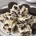 A plate of stacked oreo cookie fudge with some crumbs of Oreo cookies sprinkled on top.