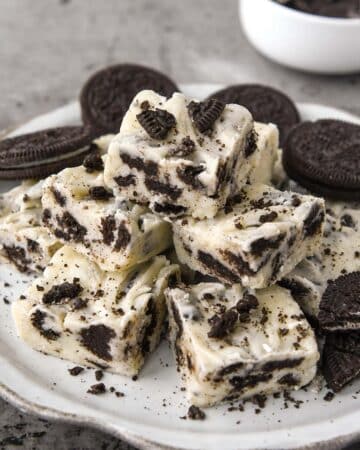 A plate of stacked oreo cookie fudge with some crumbs of Oreo cookies sprinkled on top.
