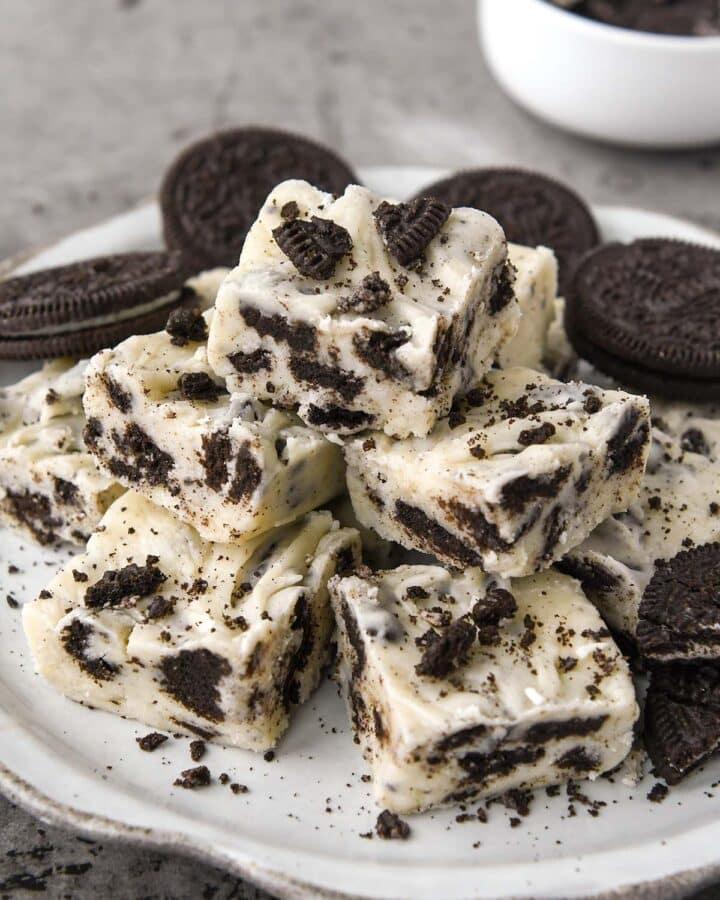 A plate of stacked oreo cookie fudge with some crumbs of Oreo cookies sprinkled on top.