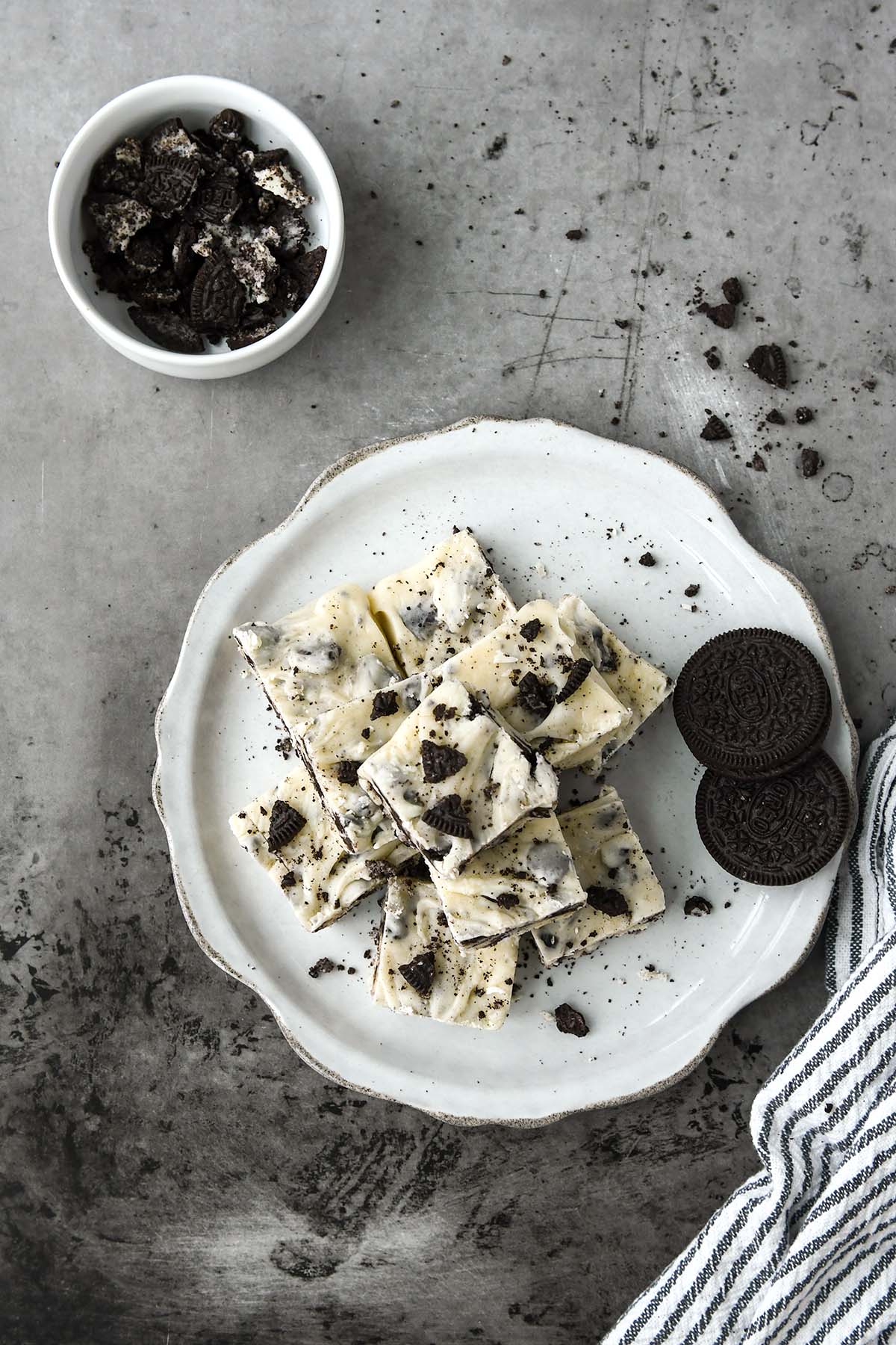 Above view of a plate of fudge with two whole Oreos and a bowl of crushed oreos.