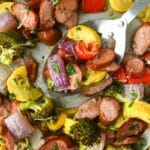 Up close and above view of baked vegetables on a sheet pan with a serving spoon.