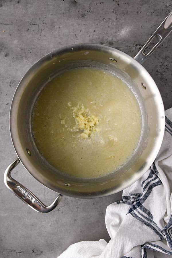 Step one to make gravy is to add flour and minced garlic to melted butter.