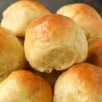A close up of a basket of buttery dinner rolls.