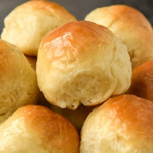 A close up of a basket of buttery dinner rolls.