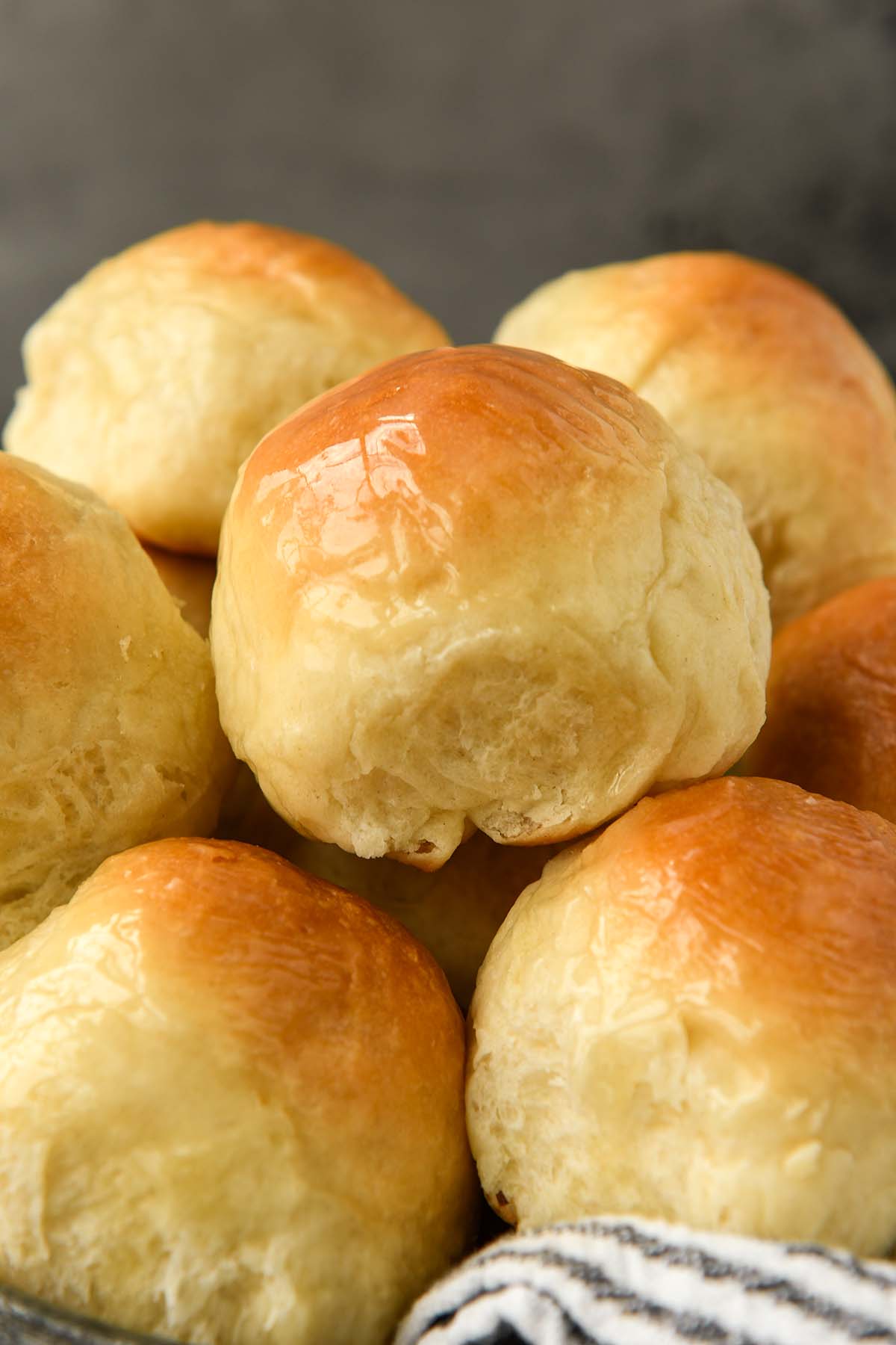 A close up of a basket of buttery dinner rolls.