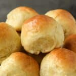 A close up of a basket of buttery dinner rolls.
