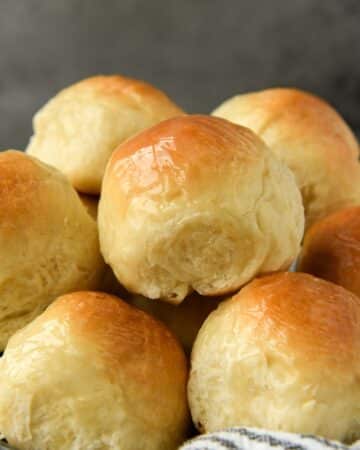 A close up of a basket of buttery dinner rolls.
