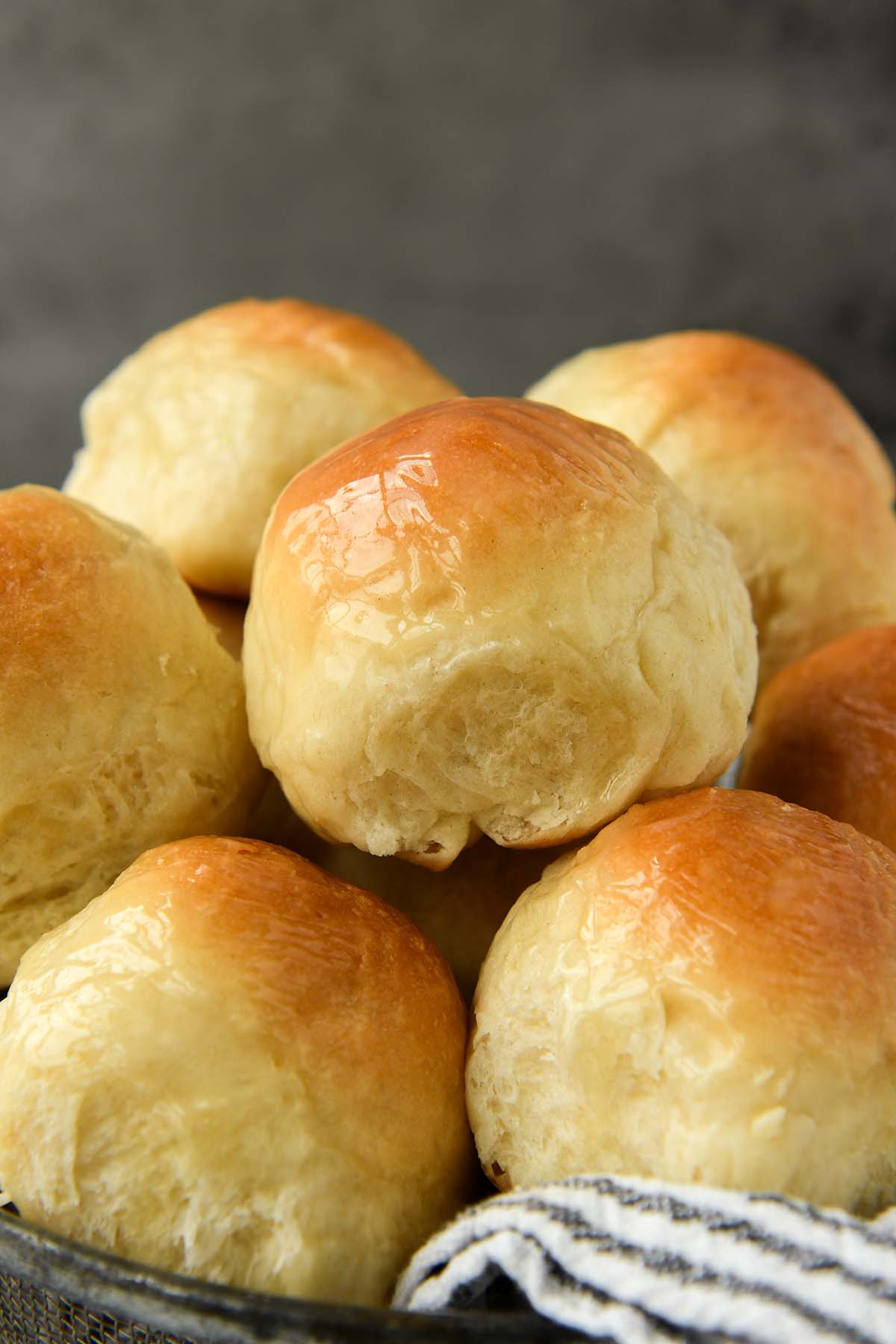 A close up of a basket of buttery dinner rolls.