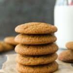 Front view of a stack of five molasses cookies with a glass of milk.