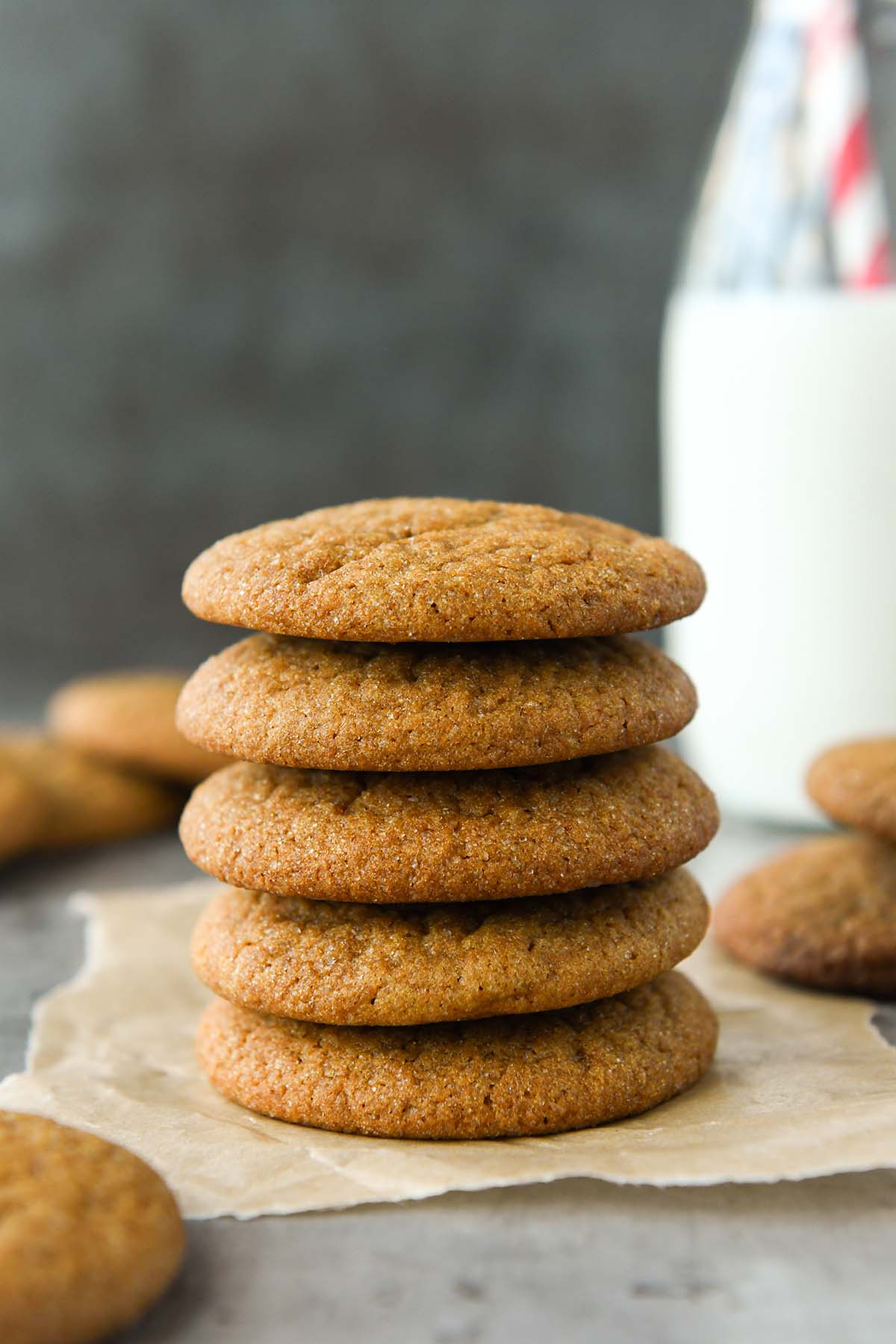 Front view of a stack of five molasses cookies with a glass of milk.