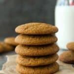 Front view of a stack of five molasses cookies with a glass of milk.