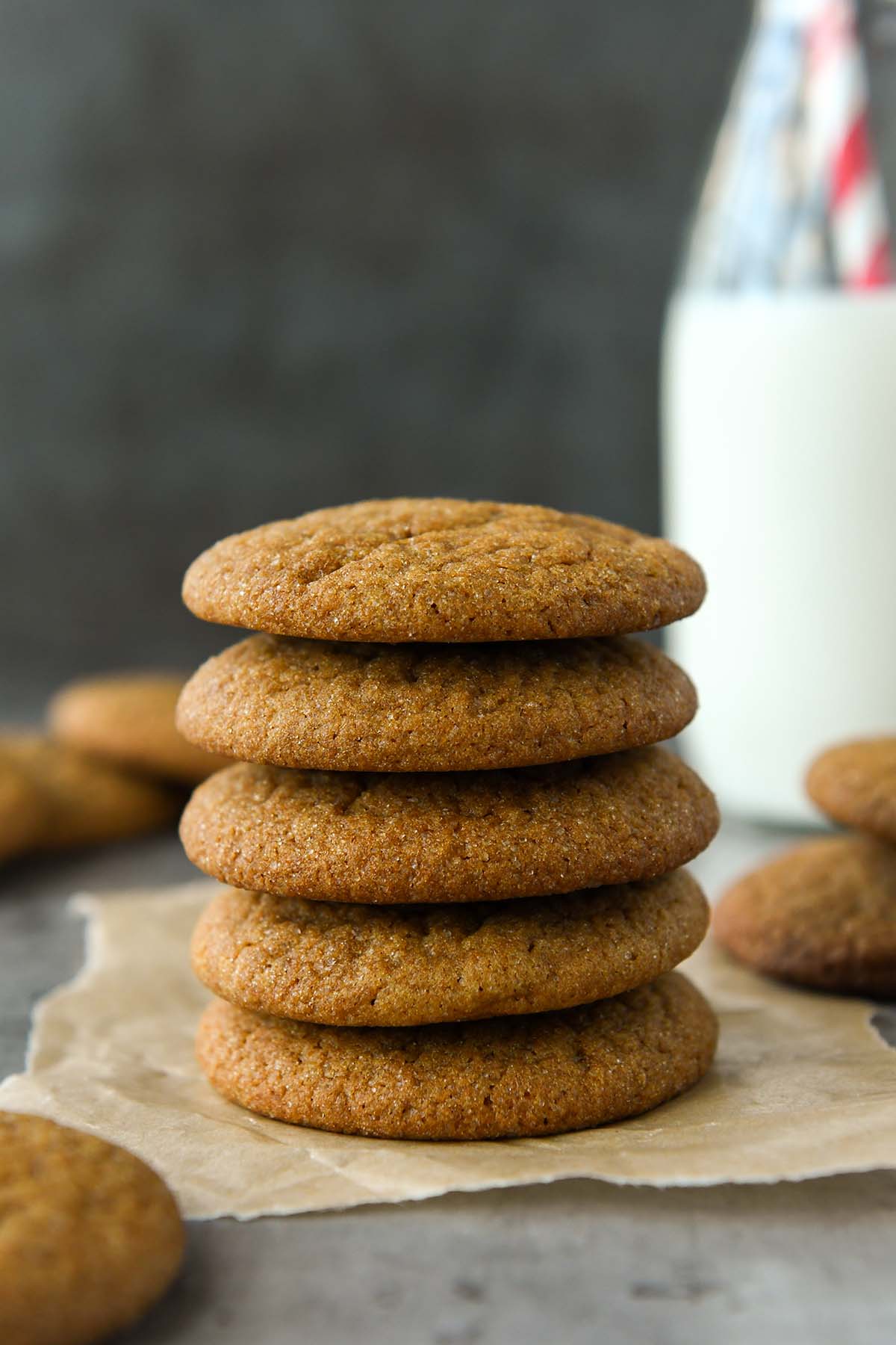 Front view of a stack of five molasses cookies with a glass of milk.