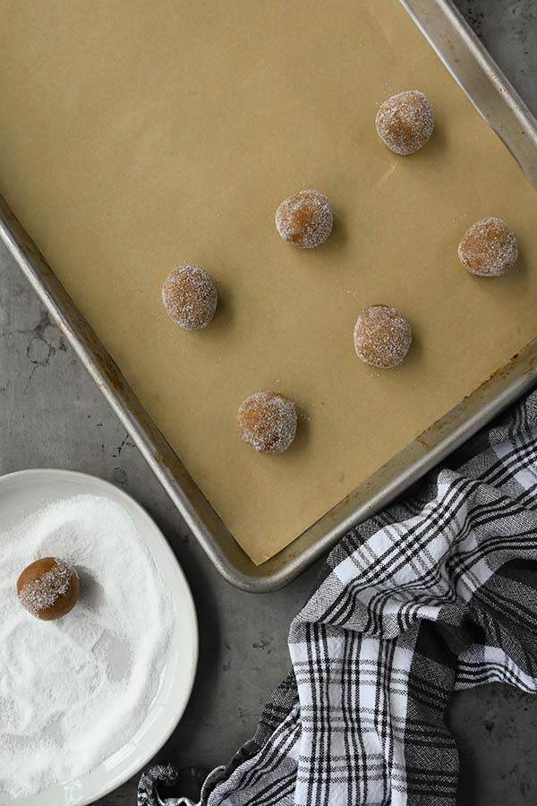 Step six the dough gets rolled into balls, rolled into sugar, and put on a baking tray.