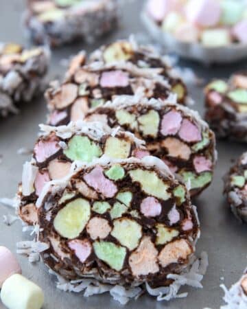 A stack of marshmallow church window cookies covered in coconut and a bowl of marshmallows in background.