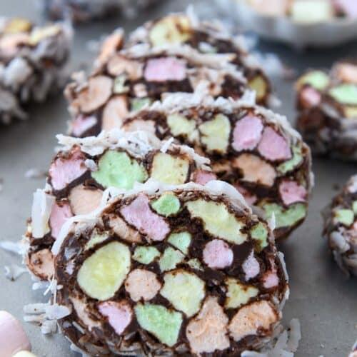 A stack of marshmallow church window cookies covered in coconut and a bowl of marshmallows in background.
