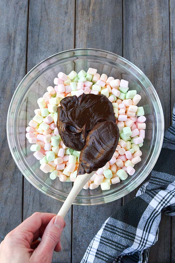 Step three is a big bowl marshmallows with the chocolate being added with a wooden spoon.
