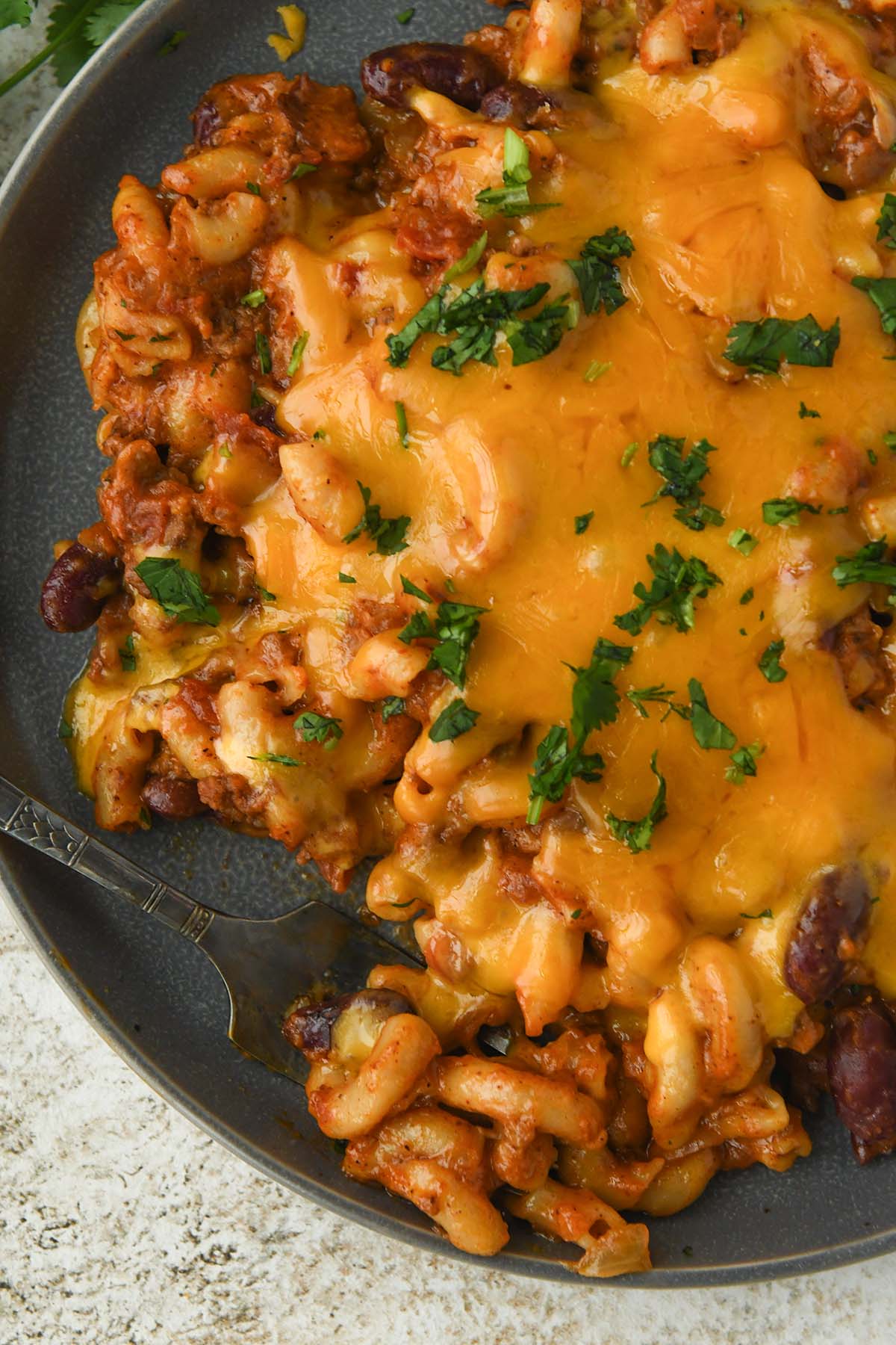 Up close above view of Chili macaroni and cheese sprinkled with cilantro with a fork.