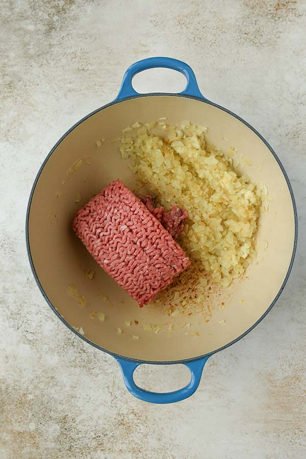 Step two is adding the ground beef in with the cooked onions.