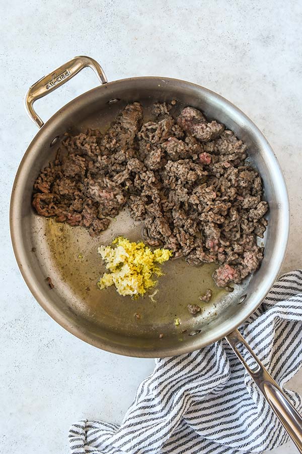 Step three is pushing the beef to the side and cooking the ginger and garlic.