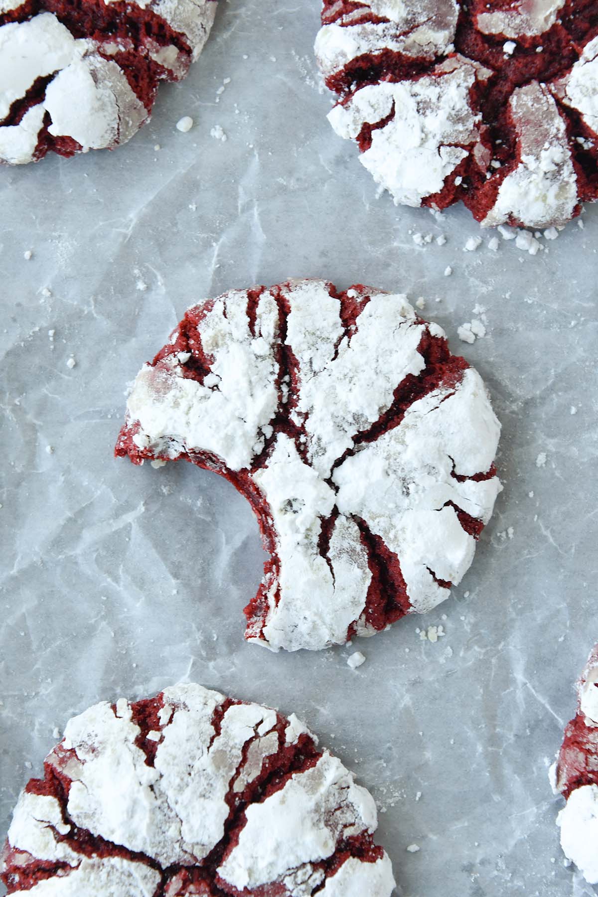 Above view of a couple red velvet crinkle cookies with a bite missing from the one in the middle.