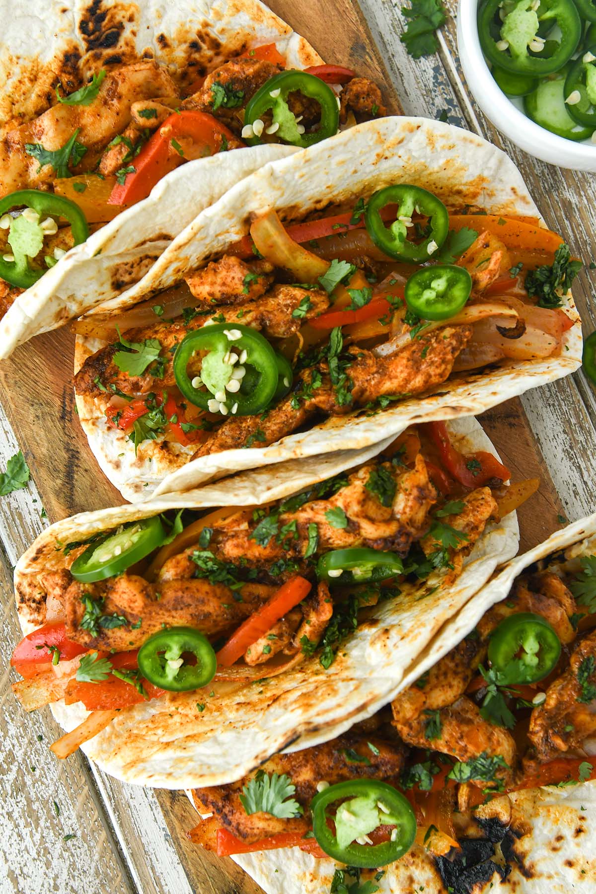 Up close and above view of fajitas sprinkled with cilantro and jalapenos.