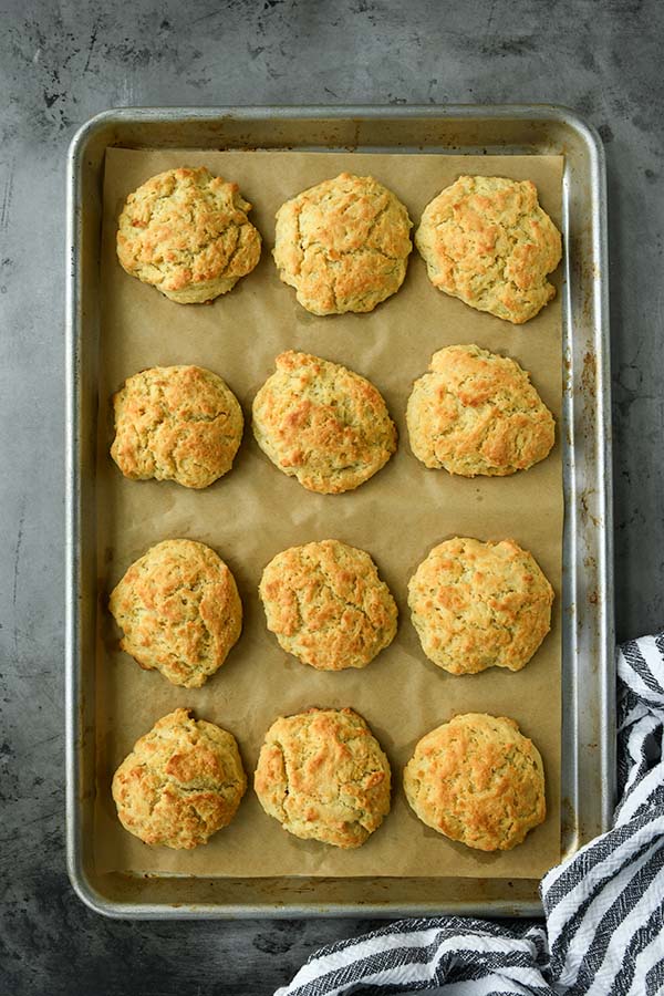 The baked biscuits on a baking sheet with a striped towel.