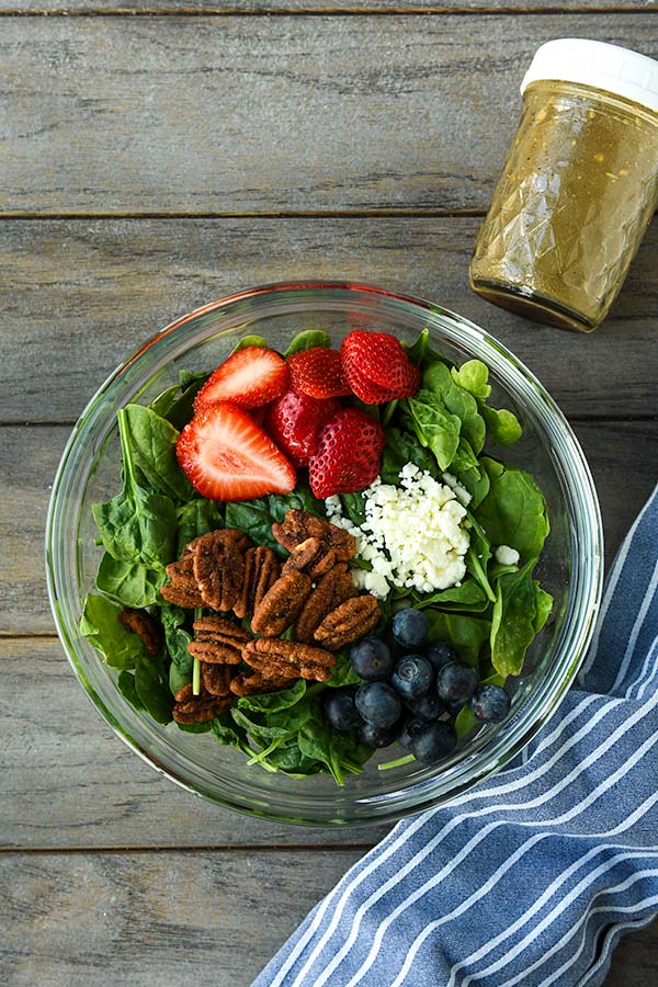Step three is all of the ingredients in a bowl to make the salad plus the dressing and a blue striped towel.