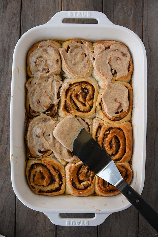 Step twelve is spreading the frosting onto the cooled rolls.