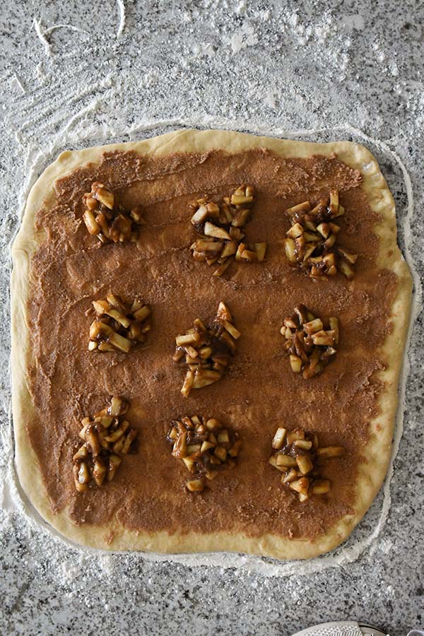 Step six is spreading the cinnamon mixture out on the dough then adding on the apple filling,.