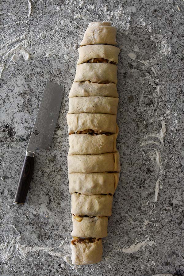 Step seven is rolling the cinnamon rolls into a roll and slicing it into pieces.