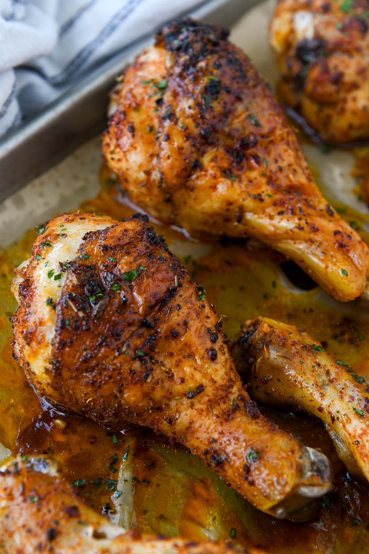 Two chicken legs on a baking sheet with a striped towel. 