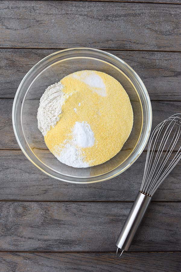Step one is a glass bowl with all of the dry ingredients in it and a whisk on the side.