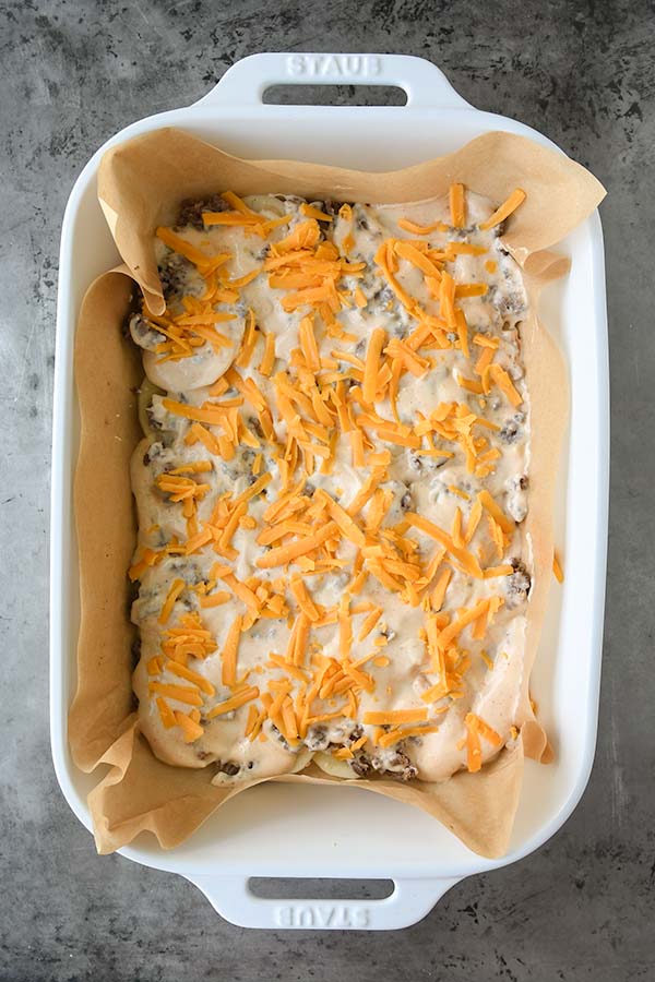 Step seven is shredded cheese added on top of the sauce.