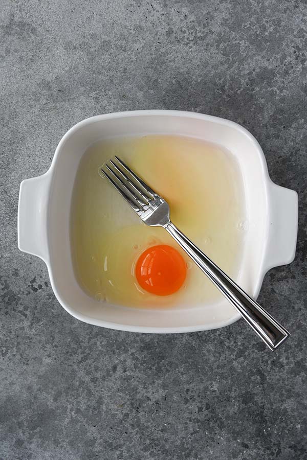 Step two is an egg and water added to a low profile dish with a fork for stirring.