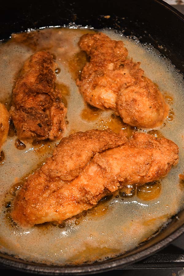 Step eight is the chicken tenders flipped over after the first side is cooked. The place them on a rack to drain.