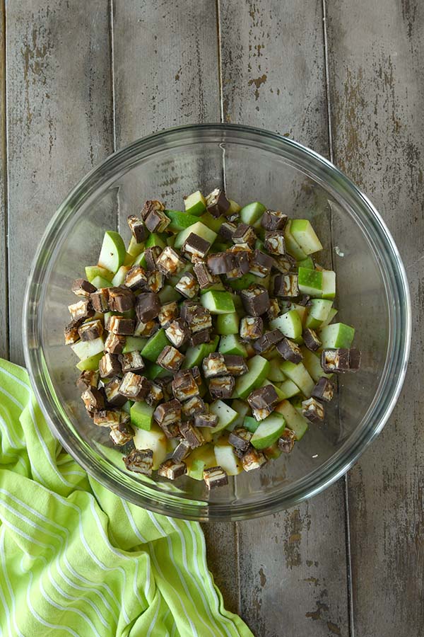 Step seven is to mix the snickers candy pieces into the apples.