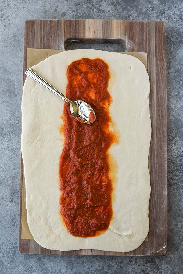Step two is spreading out the pizza sauce over the dough.