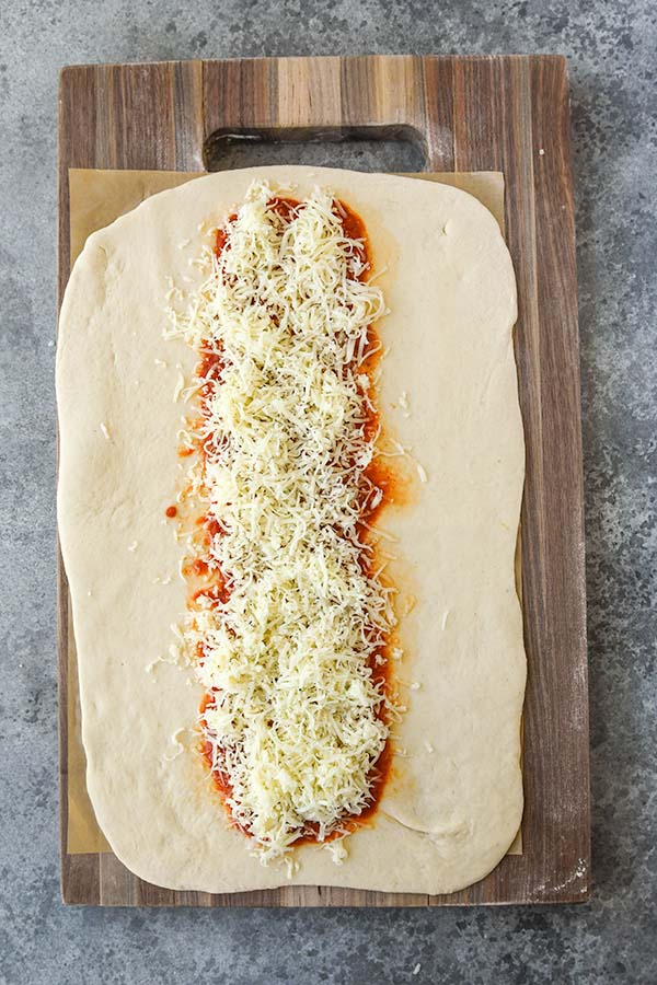 Step three is sprinkling the shredded cheese over the sauce.