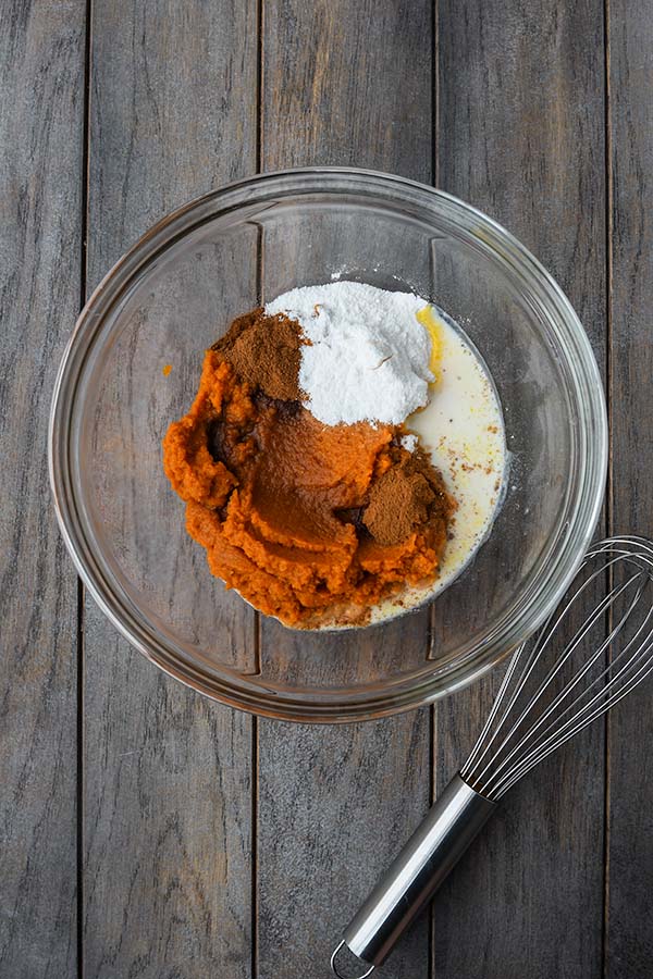 Step one is the pumpkin puree, vanilla pudding powder, spices, and milk added to a glass mixing bowl with a whisk.
