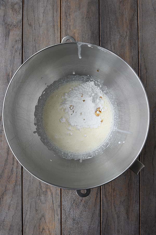 Step three is adding in the powdered sugar and vanilla to the heavy cream in the metal bowl.
